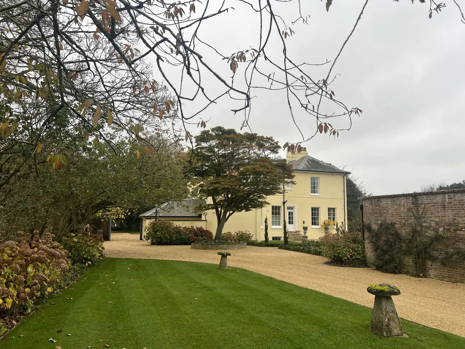 The house from within the walled garden, framed by bare branches.