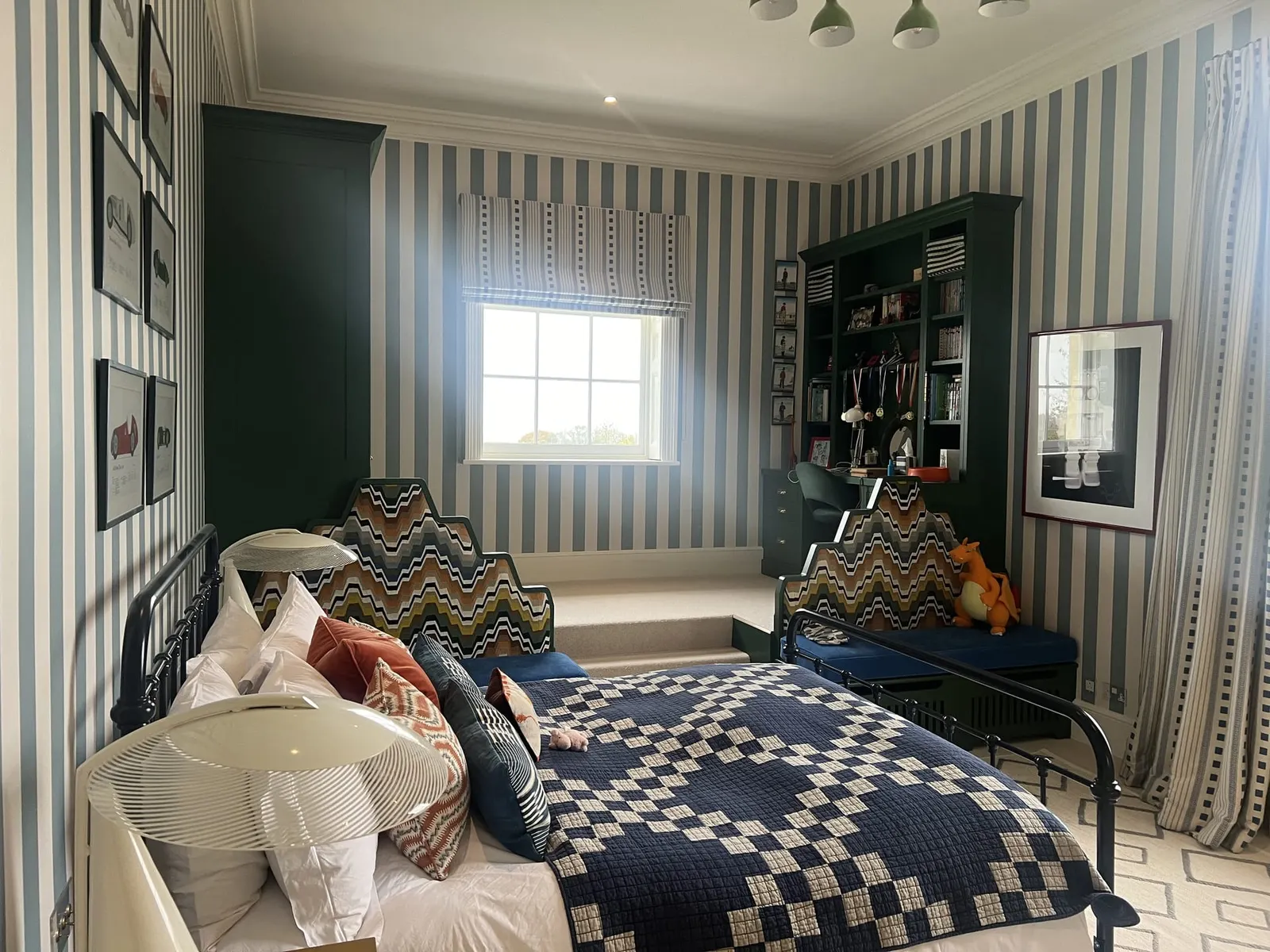 The same striped bedroom from the door, showing built-in shelving and the chequered quilt.