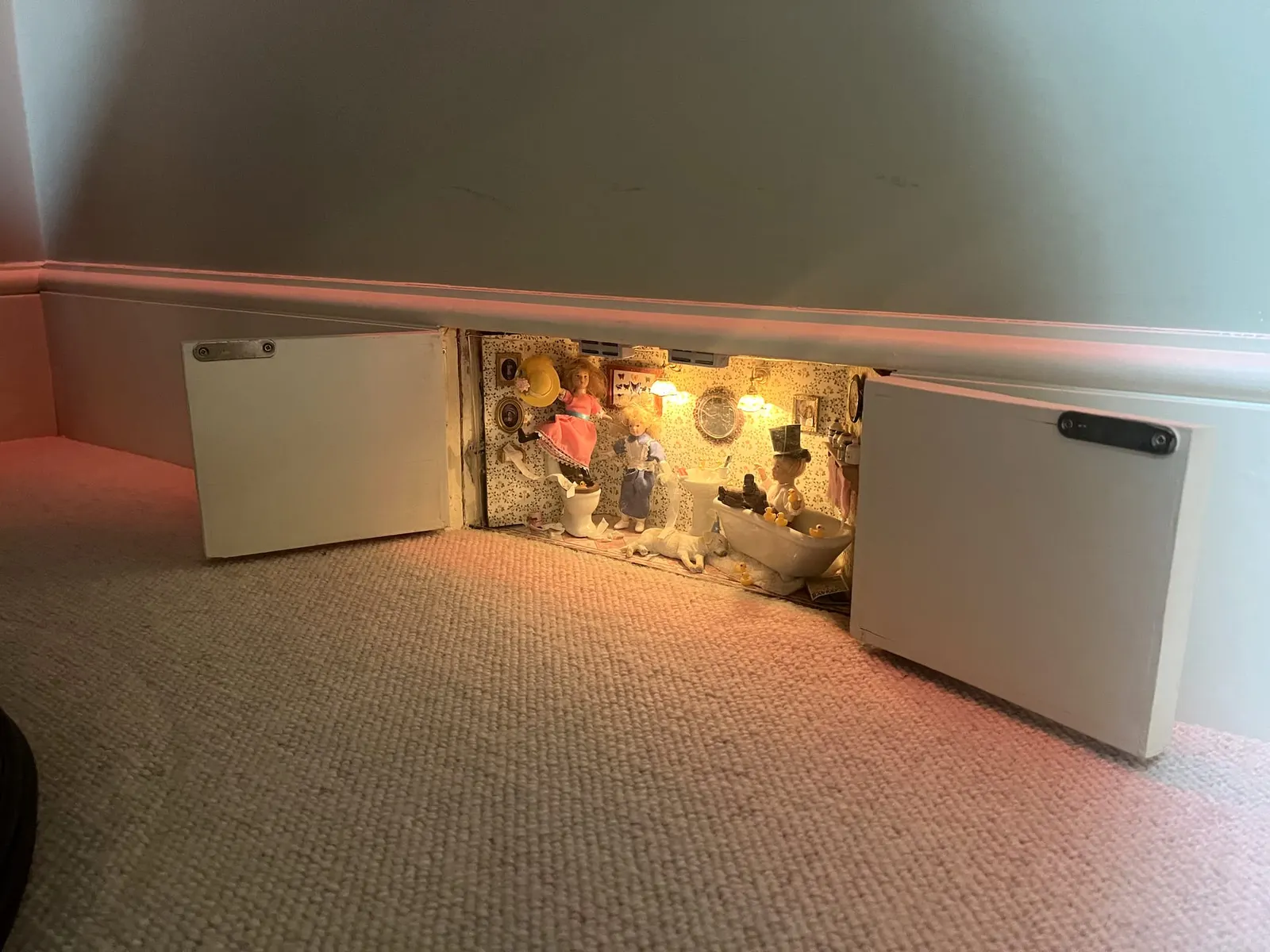 A pale carpeted room with a low painted unit set in front of a lit recess.