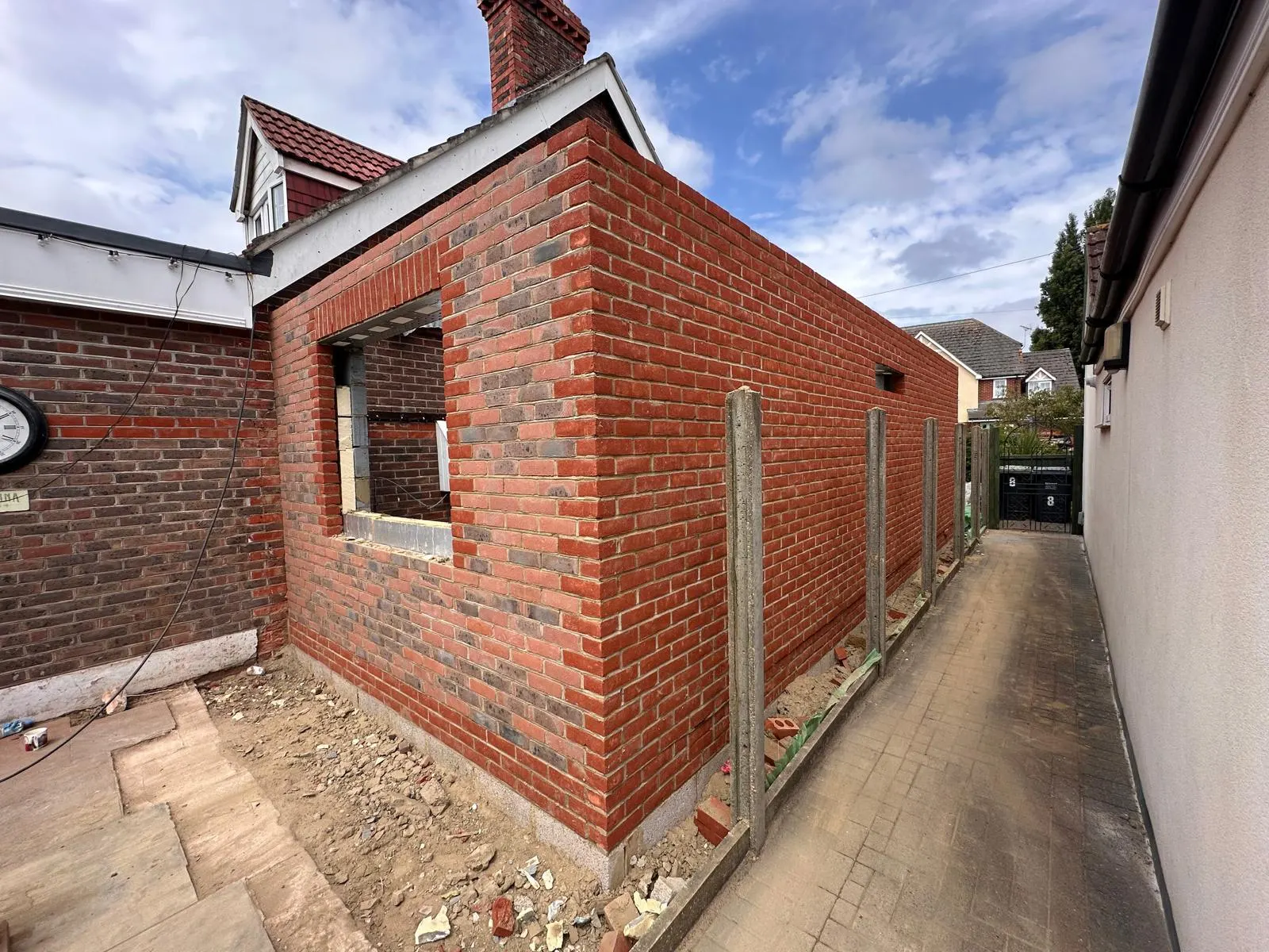 A single-storey brick extension shell down the side of a house, with a structural opening formed in the elevation.
