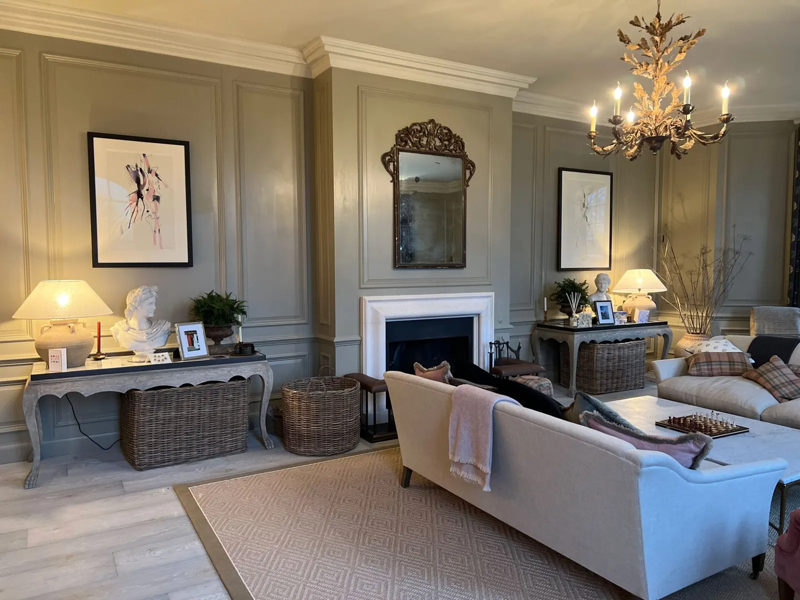 A sitting room in soft grey, with a gilt mirror over the chimneypiece and a console beneath.