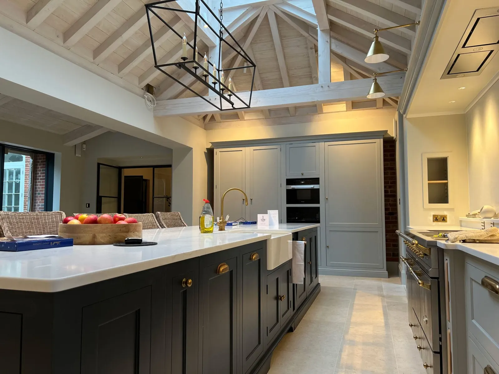 A vaulted family kitchen with painted cabinetry, a stone island and a whitewashed beamed ceiling.